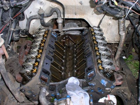 1988 Ford Bronco - Close-up of a V8 engine with valve covers off, revealing internal components and oil residue.