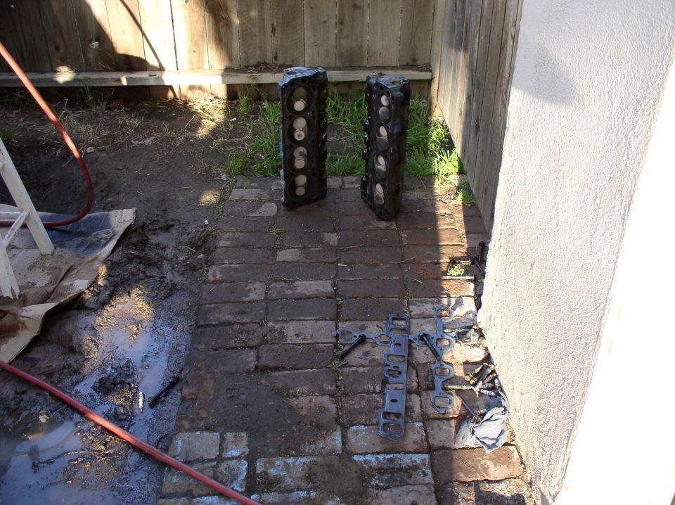 Two engine block halves and engine gaskets on a brick patio