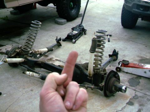 1989 Ford Bronco - Vehicle suspension components are laid out on the ground next to a jack, with another vehicle visible in the background.
