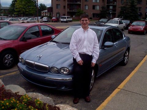1999 Ford Taurus - A man poses with his Jaguar X-Type in a parking lot, with other vehicles and an apartment building visible.