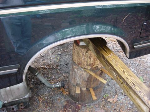 1991 Ford Bronco - Rear quarter panel of a 1991 Ford Bronco is propped up with wooden blocks and lumber.