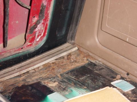 1991 Ford Bronco - Interior view of a vehicle's floor showing significant rust and damage near the door sill.