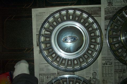 1991 Ford Crown Victoria LTD - Ford hubcaps are shown laid out on newspapers, with a prominent Ford logo on one.