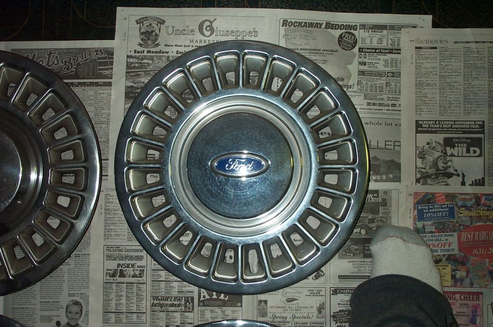 Ford hubcap with blue oval logo on newspaper background