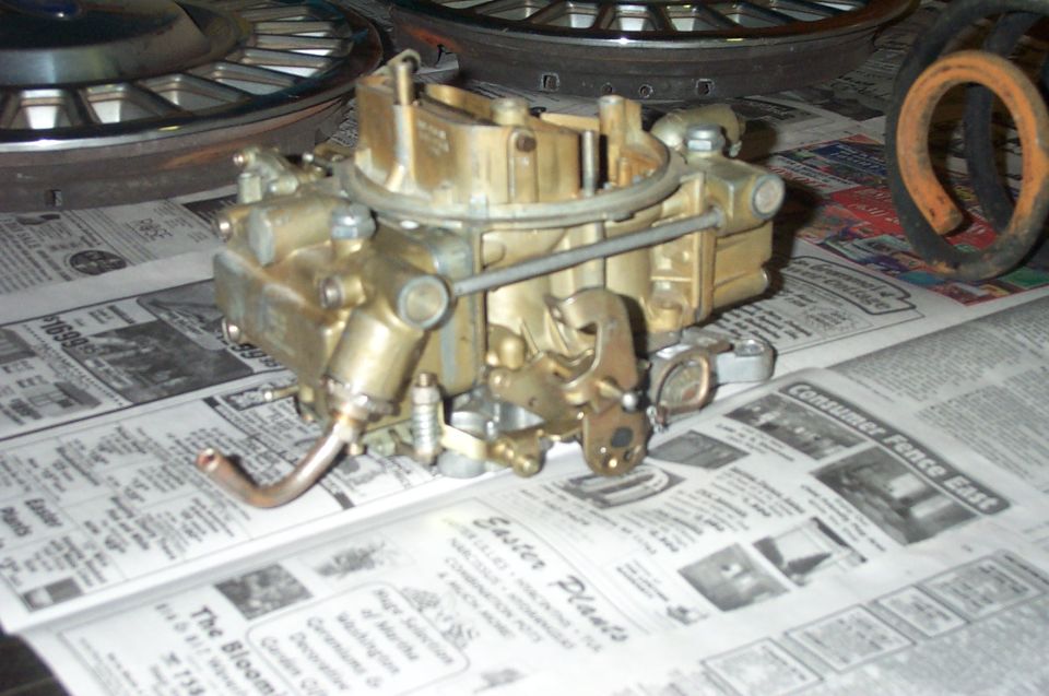 Gold carburetor with copper fuel line, resting on newspapers