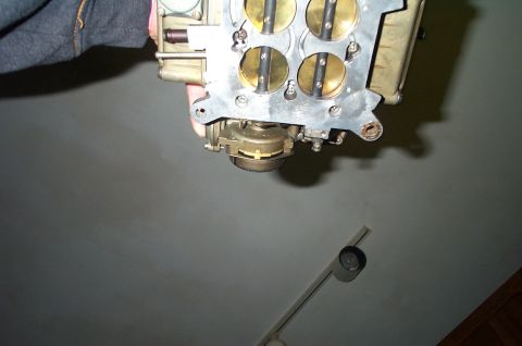 1991 Ford Crown Victoria LTD - A carburetor, likely for an older vehicle, is held up for inspection, showing its internal components.