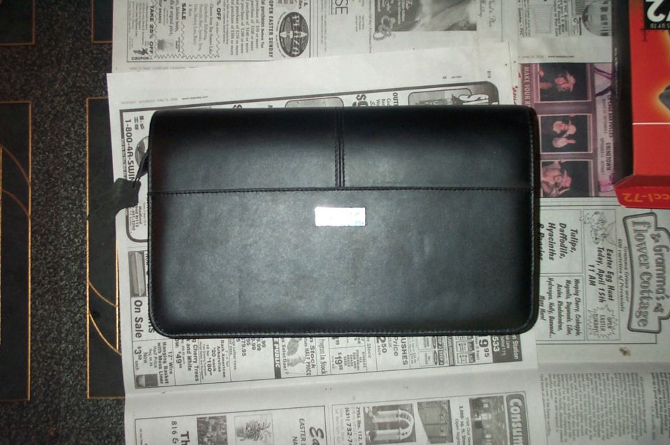 Black zippered vinyl owner's manual case lying on newspaper