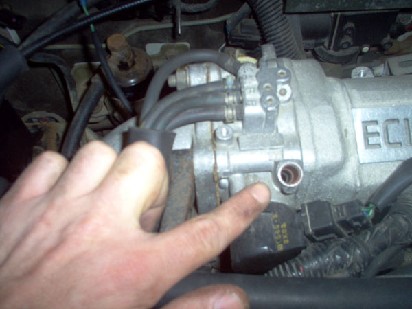 Close-up of engine ignition coil and wiring with hand visible