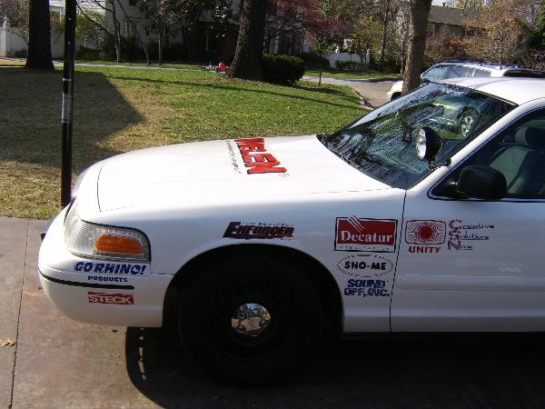 1999 Ford Crown Victoria police car with 'ENFORCER' and other decals on the hood and fender