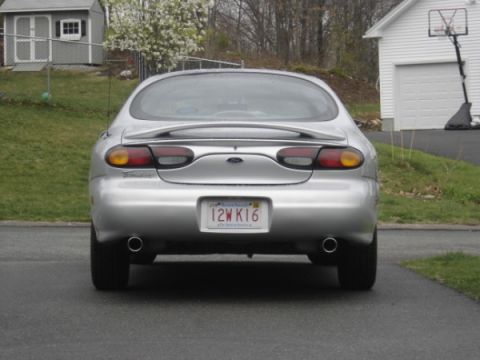1999 Ford Taurus - This silver sedan is parked in a driveway with a house and basketball hoop in the background.