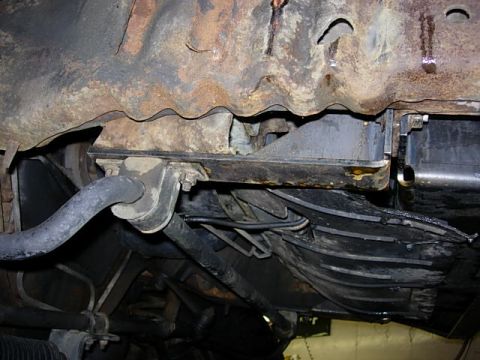 1993 Ford Bronco - Underside view of a rusty vehicle frame showing suspension components and wiring.