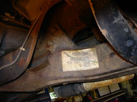 1993 Ford Bronco - A close-up view of a vehicle's undercarriage reveals a part identification sticker with various codes and numbers.