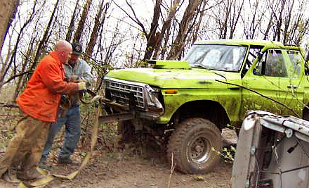 1978 Ford Bronco - Two men assist a green 1978 Ford Bronco, equipped with a winch, as it navigates rough terrain.