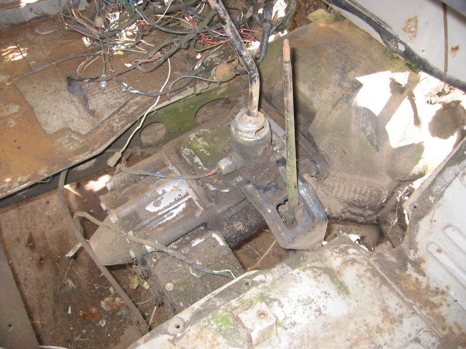 Transmission and tangled wiring harness in a dirty, possibly abandoned vehicle interior