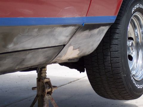 1972 Ford Ranchero - Side view of a vehicle's lower body panel being prepped for repair, with blue tape masking the area.