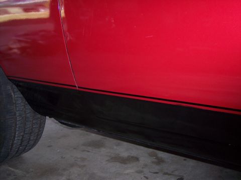 1972 Ford Ranchero - Close-up of a red vehicle's side panel showing a black stripe and part of a tire.