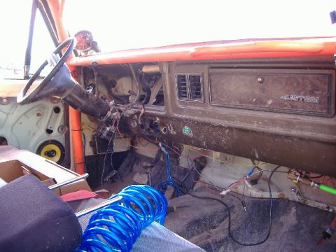 1979 Ford Bronco - The interior of a 1979 Ford Bronco shows a disassembled dashboard with exposed wiring and an orange roll cage.