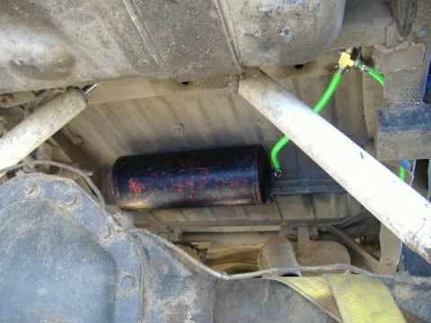 1979 Ford Bronco - Undercarriage view reveals suspension components and a cylindrical tank with green tubing attached.