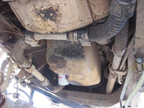 1977 Ford F-150 - Close-up of the underside of a vehicle, revealing the oil pan, various hoses, and an oil filter.