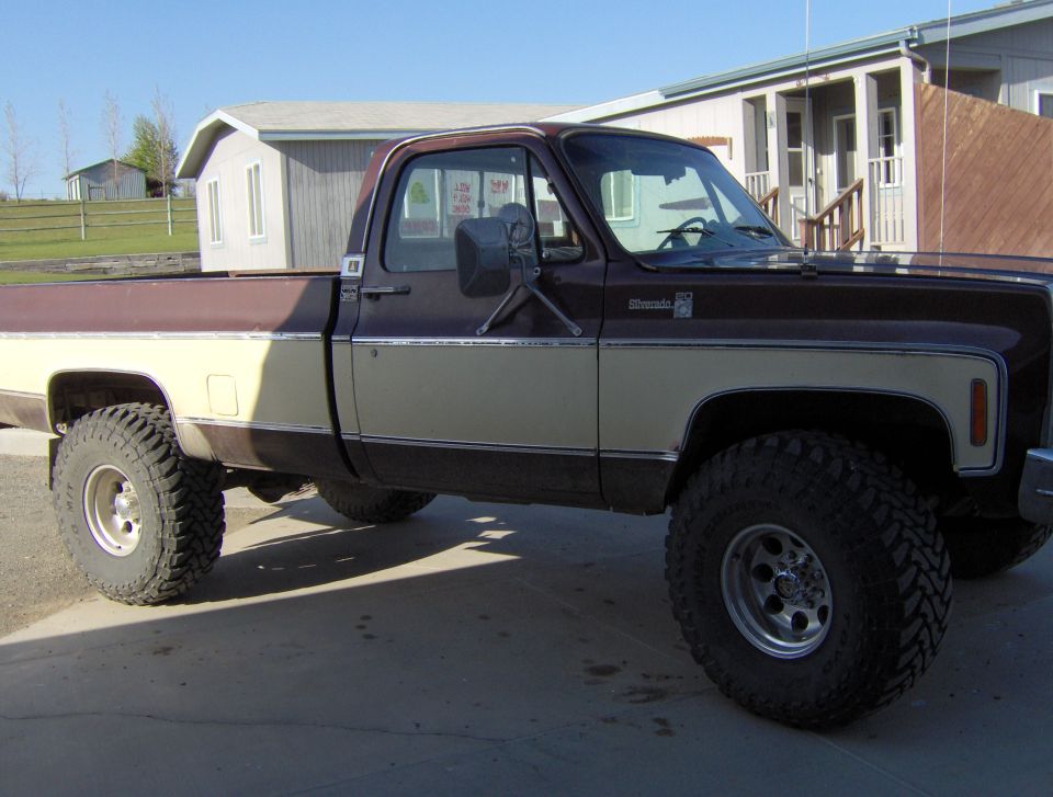 Side view of brown and tan lifted Chevrolet Silverado square-body pickup on a driveway
