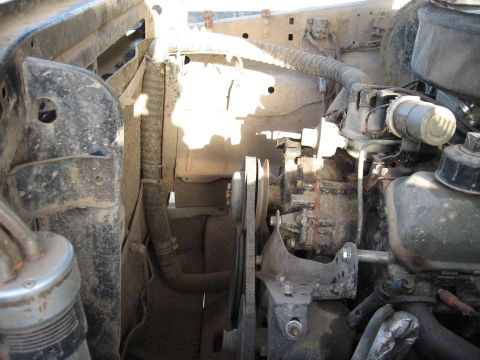 1977 Ford F-150 - Close-up view of a dirty engine bay, showing various mechanical parts and hoses.