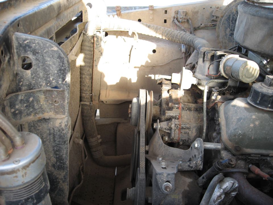 Engine bay of a dusty truck with visible radiator, belts, and engine components