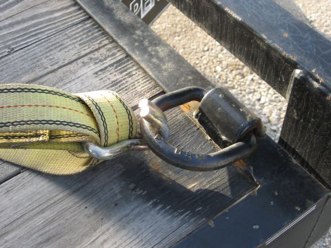 1977 Ford F-150 - Close-up of a tie-down strap attached to a D-ring on a trailer deck.