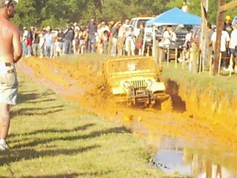 1978 Ford Bronco - A yellow Jeep Wrangler navigates a muddy track during an off-road event.