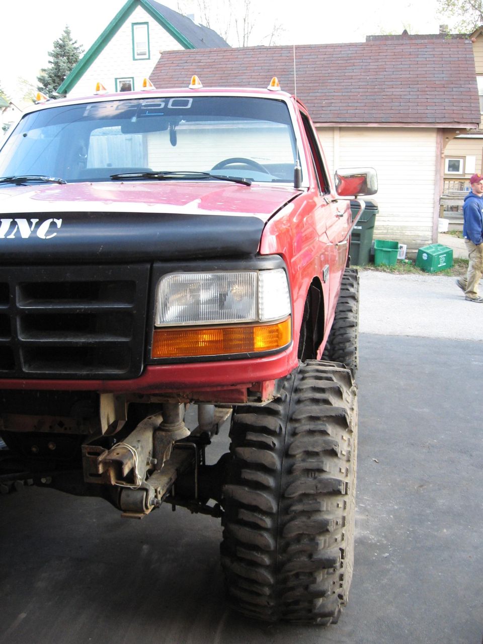 Red Ford F-150 pickup truck with lifted suspension and large off-road tires, front quarter view