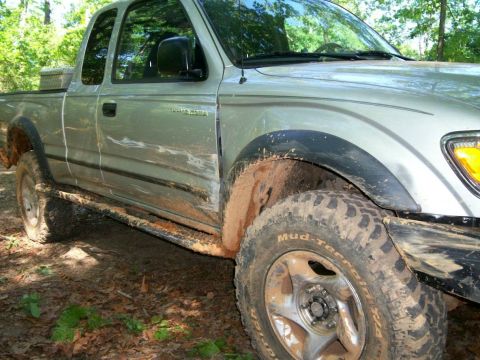 1993 Ford Bronco - A muddy silver pickup truck is seen from the side, equipped with off-road tires.