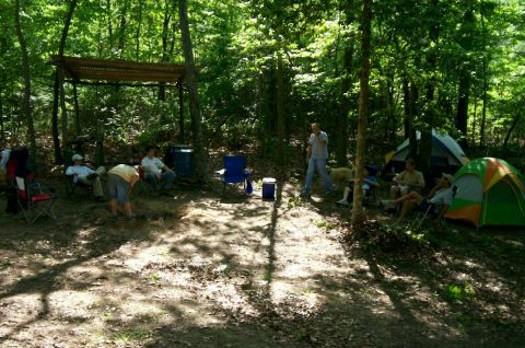 1993 Ford Bronco - A group enjoys a weekend camping trip in a wooded area, with tents set up and people relaxing in chairs.