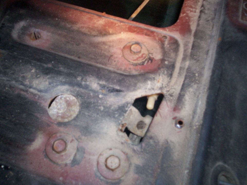 Rusty metal panel with bolts, a bracket and white plastic clip in an open slot