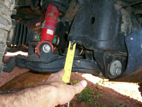 1993 Ford Bronco - Underbody shot of a front suspension with a red-bodied strut/shock bolted through a lower control arm, a black CV boot and coil spring behi…