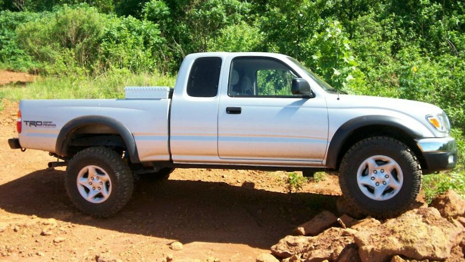 Silver Toyota Tacoma pickup truck with TRD badging, driving on rough terrain