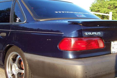 1993 Ford Taurus - Rear view of a dark blue 1993 Ford Taurus sedan, showing the taillight and spoiler.