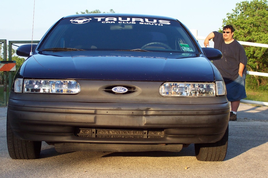 Dark blue 1992 Ford Taurus front view, with a man leaning on the driver's side door