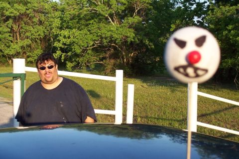1993 Ford Taurus - A man poses for a photo with a clown-faced lollipop obscuring the view of the car's front end.