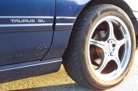 1993 Ford Taurus - Close-up of the side panel and wheel of a blue Ford Taurus GL.
