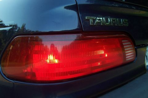 1993 Ford Taurus - The rear of a dark-colored Ford Taurus is shown, focusing on the tail light assembly and the model name badge.