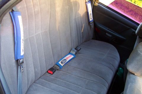1993 Ford Taurus - The interior of a car shows the rear seat with blue seatbelt covers Ford Racing branding.