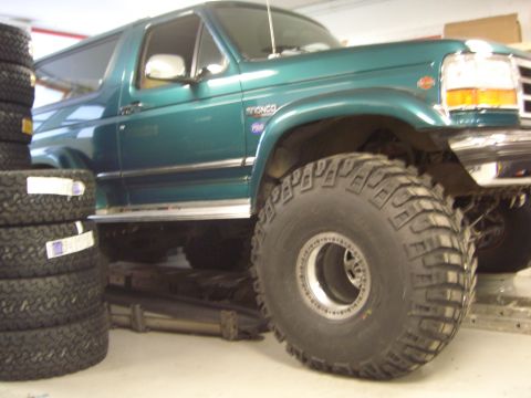 1996 Ford Bronco - A green 1996 Ford Bronco is shown with large off-road tires, possibly in a garage or workshop.