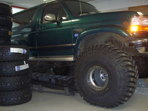 1996 Ford Bronco - A green 1996 Ford Bronco is shown with large off-road tires, possibly undergoing modifications.
