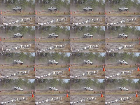 1989 Ford Bronco - A white pickup truck navigates a dirt track during a race, kicking up dust.