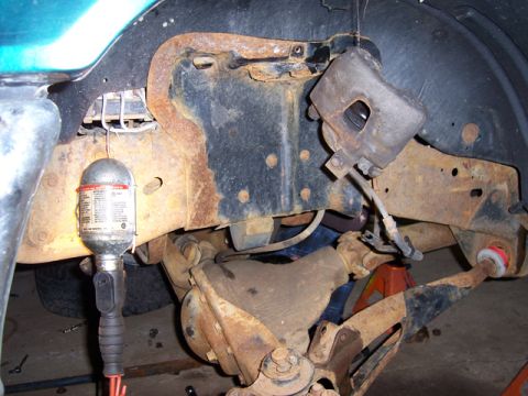 1996 Ford Bronco - Detail view of the rusty suspension and brake system, with a work light illuminating the components.
