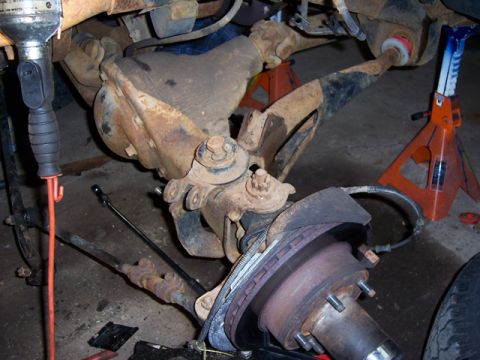 1996 Ford Bronco - Close-up view of a vehicle's front axle and suspension system, likely undergoing maintenance or modification.