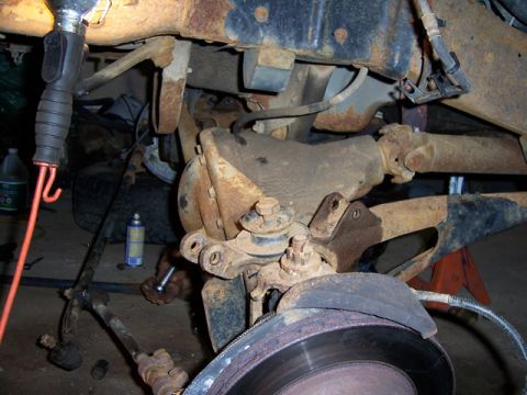 1996 Ford Bronco - Close-up view of heavily rusted vehicle suspension components, including a lifted suspension part and brake rotor.