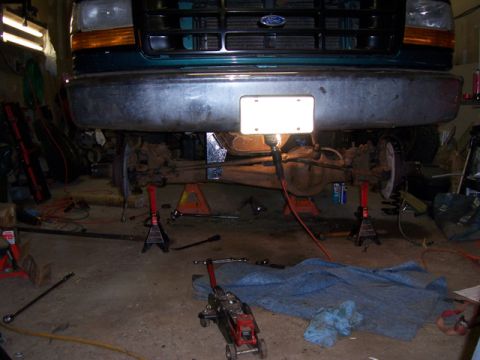 1996 Ford Bronco - Front axle and suspension of a 1996 Ford Bronco being worked on in a garage.