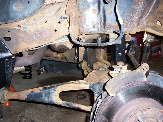 Truck front suspension with radius arm and new black drop bracket, brake rotor and knuckle visible