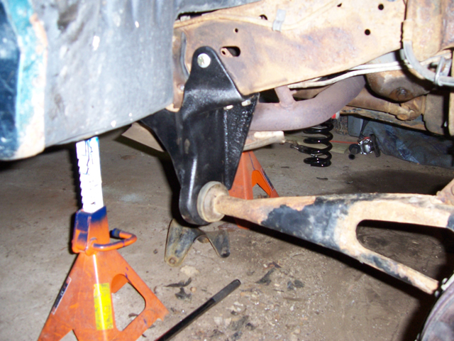Black lift drop bracket and radius arm with new bushing under truck frame on jack stands