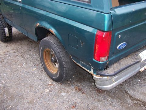 1996 Ford Bronco - Rear view of a 1996 Ford Bronco with visible rust on the body and bumper.